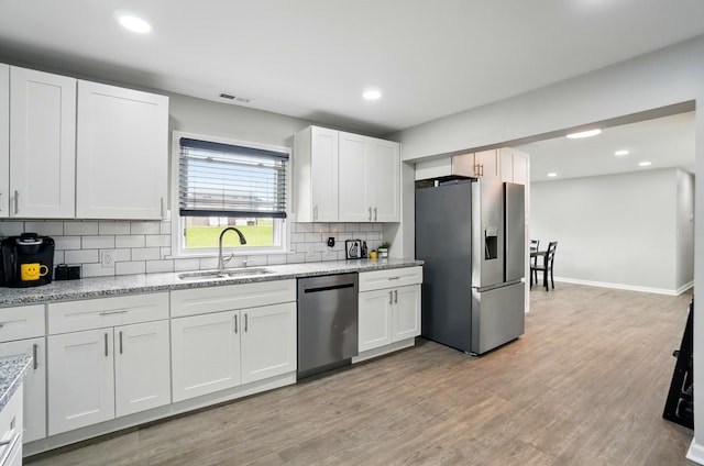kitchen with visible vents, white cabinets, a sink, backsplash, and stainless steel appliances