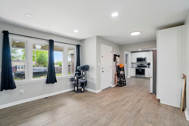 interior space featuring baseboards, visible vents, a healthy amount of sunlight, and light wood-type flooring