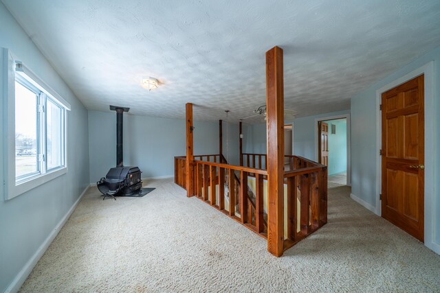 below grade area with carpet floors, a wood stove, baseboards, and a textured ceiling