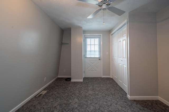 interior space featuring visible vents, dark carpet, ceiling fan, a textured ceiling, and baseboards