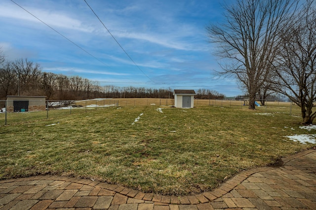 view of yard with a rural view, an outdoor structure, fence, and a storage unit