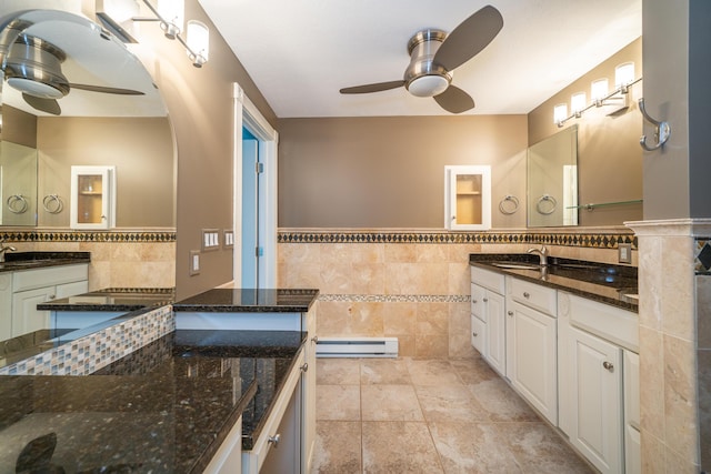 bathroom featuring a baseboard radiator, vanity, a ceiling fan, tile walls, and wainscoting