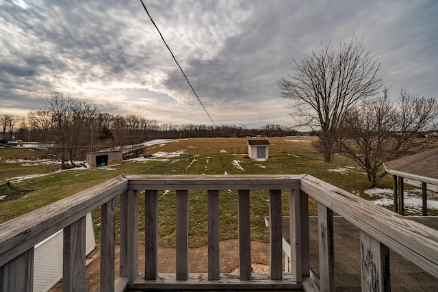 wooden deck featuring an outbuilding, a shed, and a lawn