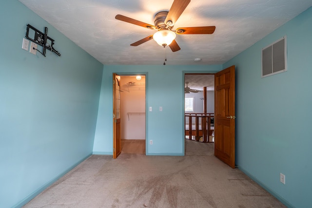 unfurnished bedroom featuring light colored carpet, visible vents, baseboards, a spacious closet, and a closet