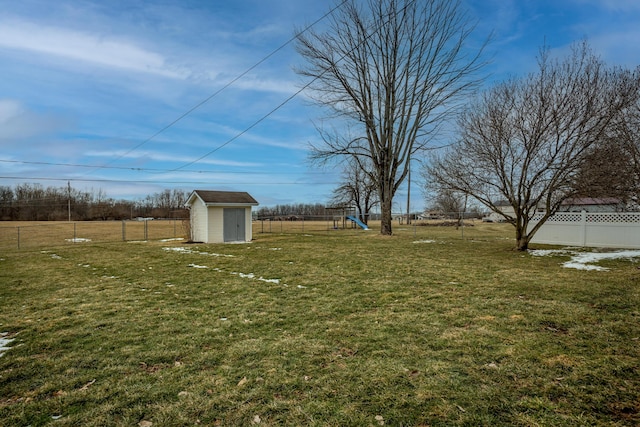 view of yard with an outbuilding, a rural view, a playground, fence, and a shed