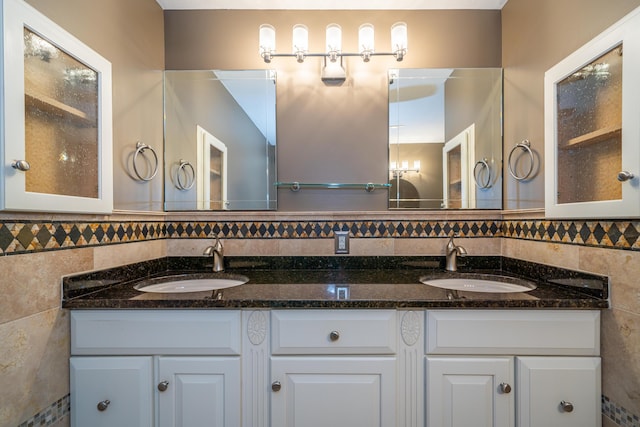 full bathroom with double vanity, tile walls, and a sink