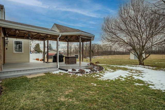 yard covered in snow featuring ceiling fan, fence, and a deck