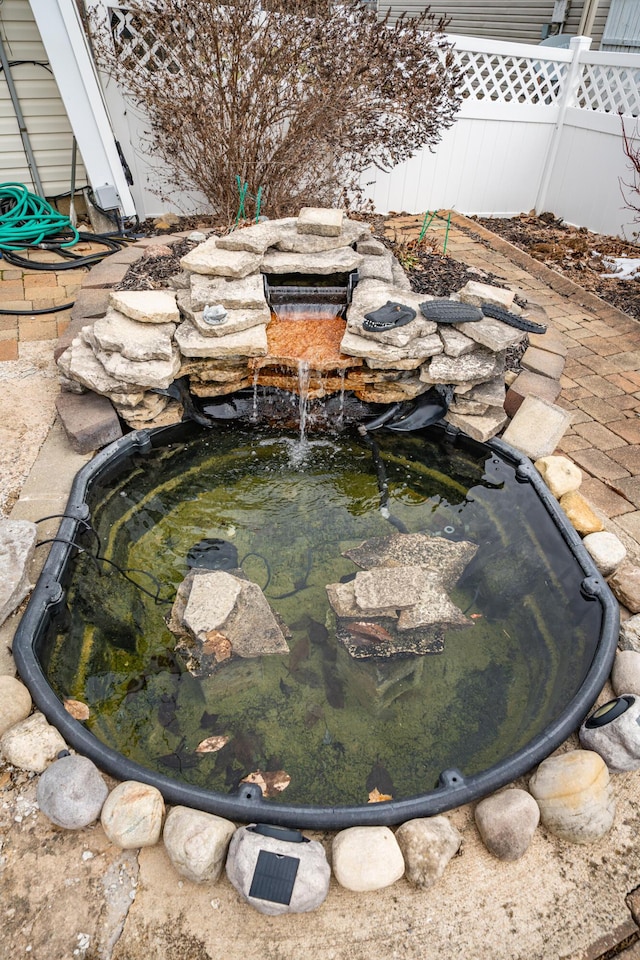 details featuring fence and a garden pond