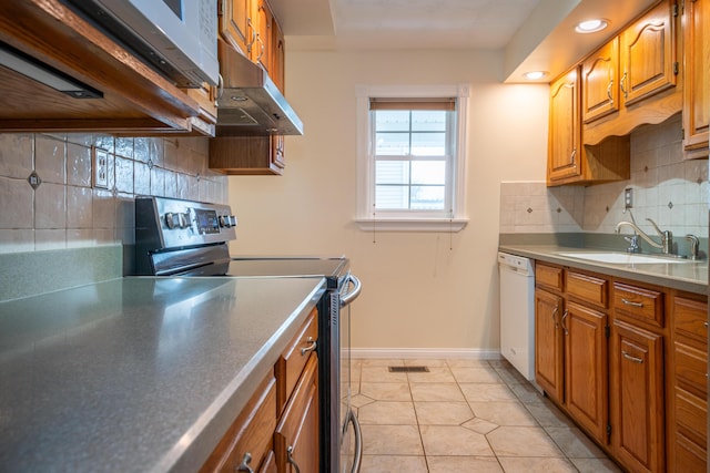 kitchen featuring electric stove, brown cabinetry, a sink, dishwasher, and under cabinet range hood