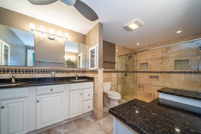 full bathroom with a tile shower, a sink, tile walls, and double vanity