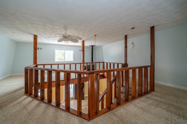 stairs with a ceiling fan, carpet, a textured ceiling, and baseboards