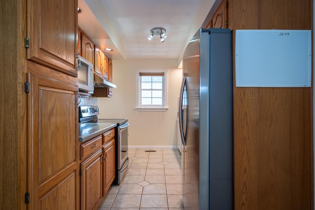 kitchen featuring light tile patterned floors, under cabinet range hood, appliances with stainless steel finishes, and brown cabinets