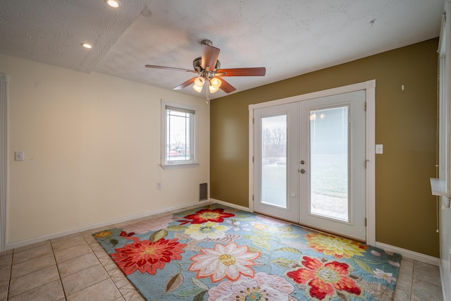 entryway featuring baseboards, ceiling fan, a textured ceiling, french doors, and light tile patterned flooring