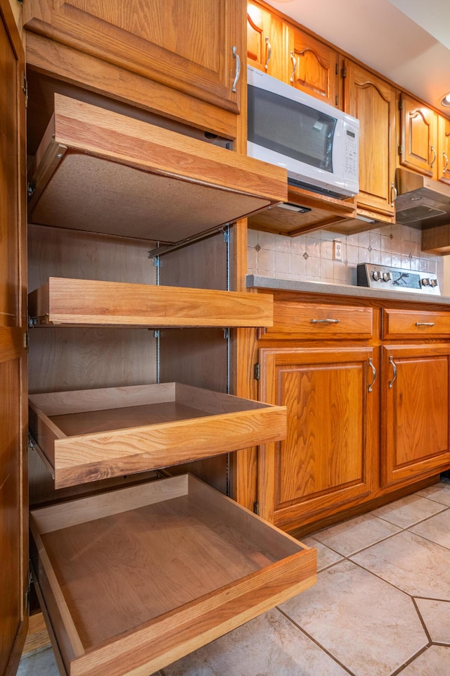 kitchen with light countertops, white microwave, brown cabinetry, and backsplash