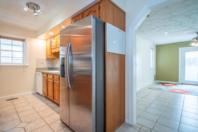 kitchen featuring white dishwasher, visible vents, stainless steel fridge with ice dispenser, light countertops, and decorative backsplash