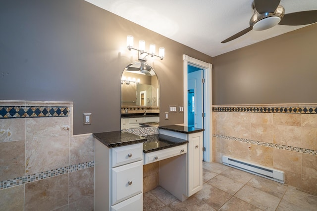 bathroom with baseboard heating, wainscoting, tile walls, and a ceiling fan