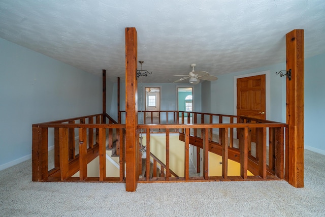 stairway featuring a textured ceiling, baseboards, and carpet flooring