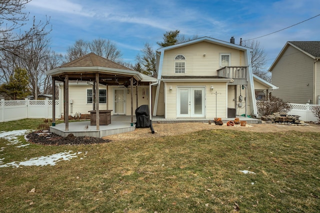 rear view of house featuring a gazebo, french doors, a lawn, and fence