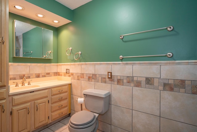 bathroom featuring tile walls, recessed lighting, toilet, vanity, and tile patterned flooring