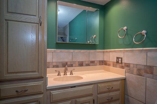 bathroom with tile walls, wainscoting, vanity, and a textured ceiling