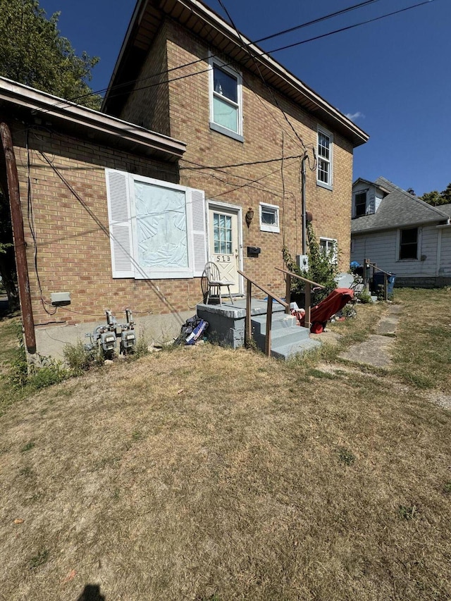 rear view of house with a lawn and brick siding