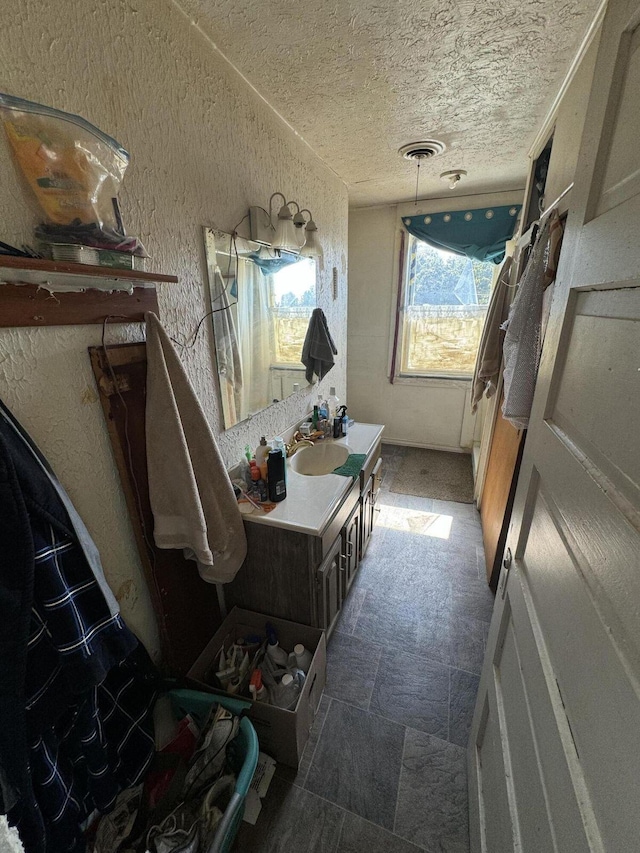 bathroom featuring a textured ceiling, vanity, and visible vents