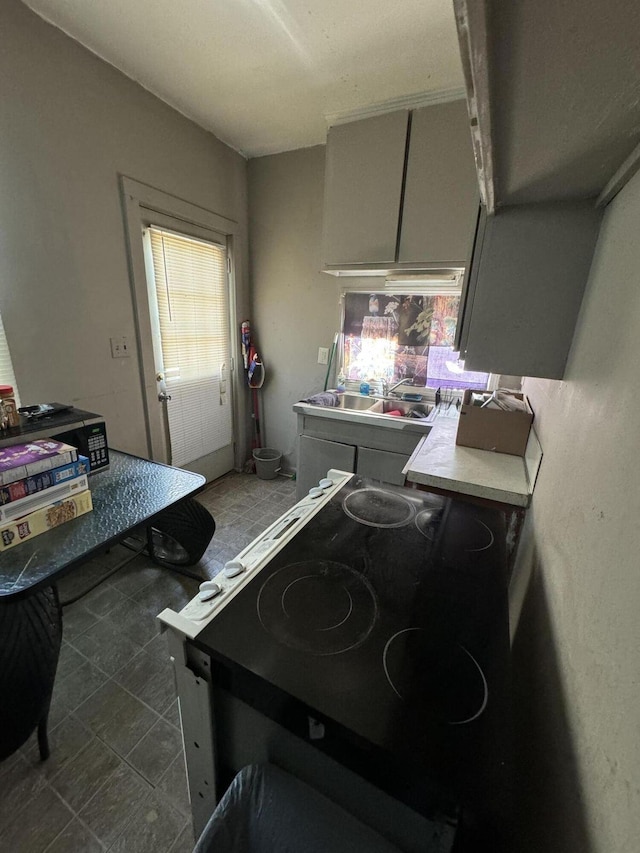 kitchen featuring electric stove, a sink, and light countertops