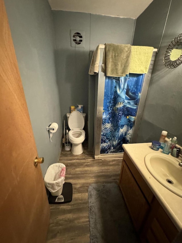 bathroom with toilet, wood finished floors, and vanity