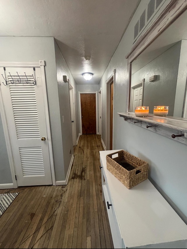 hallway with dark hardwood / wood-style flooring and a textured ceiling