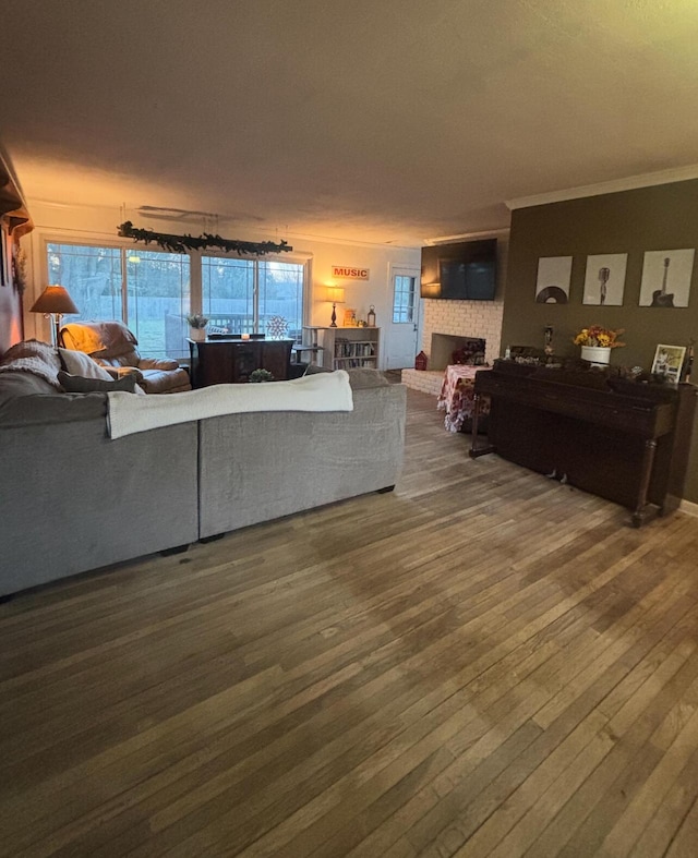 living room with hardwood / wood-style flooring, ornamental molding, and a brick fireplace