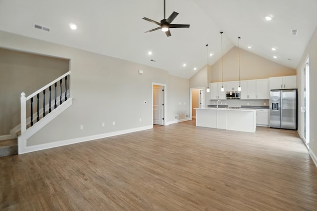 1505 Kingsgate Rd, Springfield, OH 45503 - unfurnished living room featuring a sink, high vaulted ceiling, a ceiling fan, light wood-style flooring, and stairway
