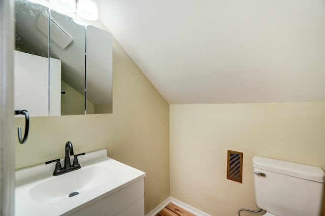 bathroom featuring visible vents, toilet, baseboards, lofted ceiling, and vanity