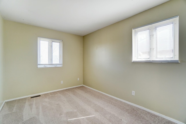 unfurnished room with carpet, visible vents, and baseboards