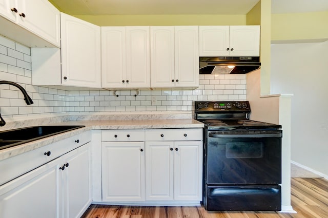 kitchen with light countertops, black / electric stove, under cabinet range hood, and a sink