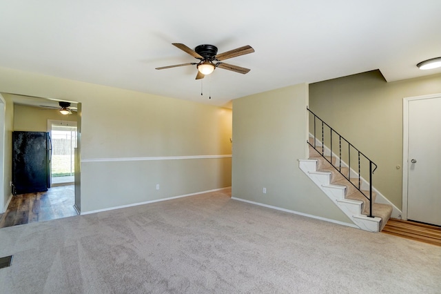 unfurnished living room featuring visible vents, baseboards, carpet floors, ceiling fan, and stairs