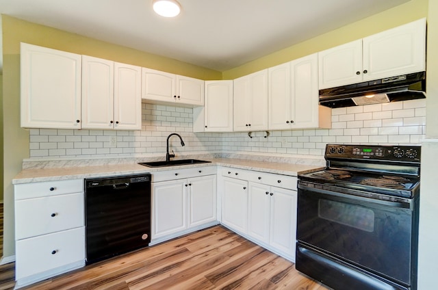 kitchen featuring black appliances, white cabinets, under cabinet range hood, and a sink