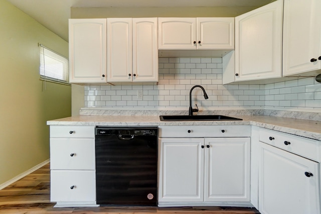 kitchen with decorative backsplash, white cabinets, black dishwasher, and a sink