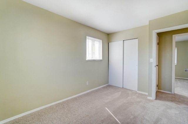 unfurnished bedroom with a closet, baseboards, and light colored carpet