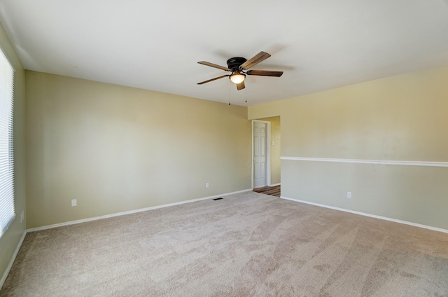 carpeted empty room featuring baseboards, visible vents, and ceiling fan