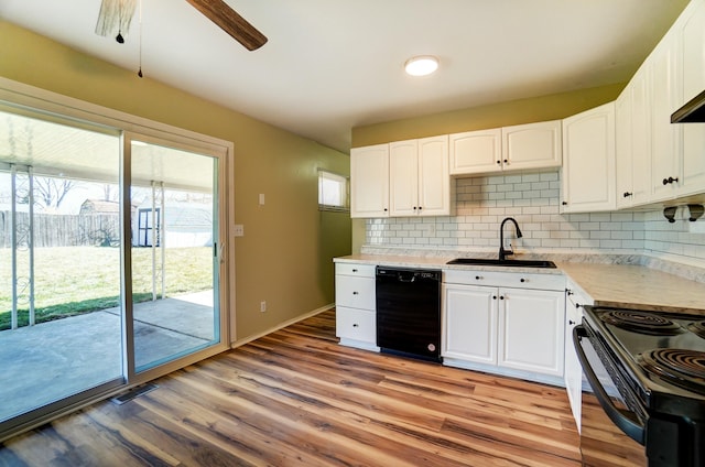 kitchen featuring light wood-style flooring, a sink, black appliances, white cabinets, and backsplash