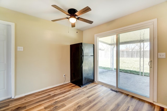 empty room featuring visible vents, baseboards, light wood finished floors, and ceiling fan