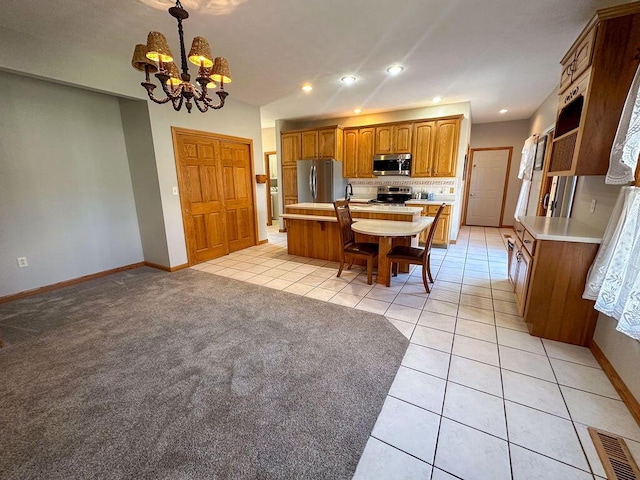 kitchen featuring visible vents, a kitchen island with sink, light countertops, a notable chandelier, and stainless steel appliances