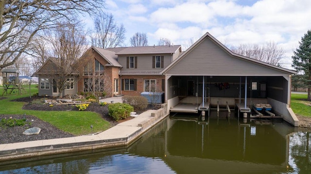 rear view of property with a patio, a sunroom, brick siding, a lawn, and a water view