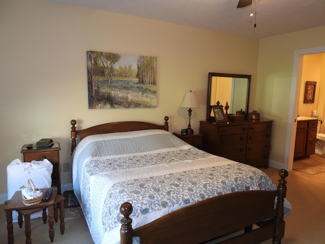 bedroom with baseboards, light carpet, and ensuite bath