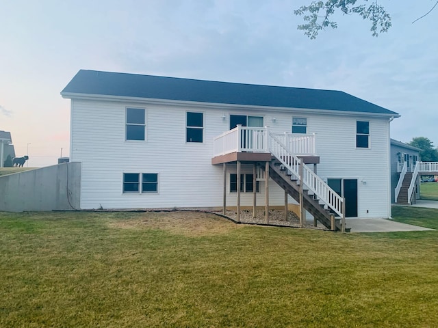 back of property with a deck, a yard, and stairway