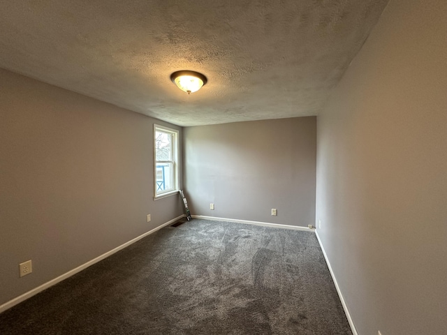 spare room with a textured ceiling and dark colored carpet