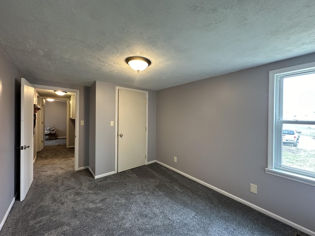 unfurnished bedroom featuring a textured ceiling and dark colored carpet