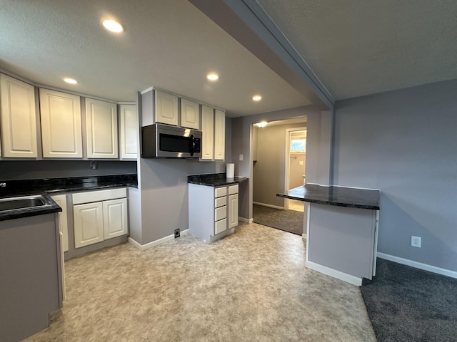 kitchen with white cabinetry, sink, light colored carpet, and kitchen peninsula