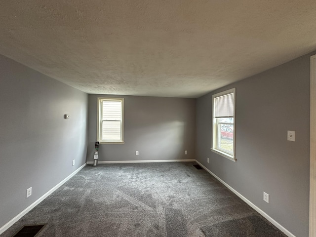 spare room featuring dark colored carpet and a textured ceiling