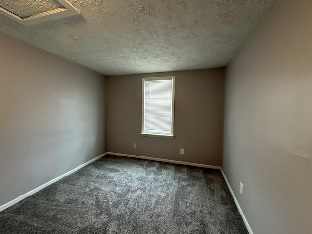 spare room featuring dark carpet and a textured ceiling